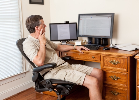 Managing remote teams - a man working from home in shorts with desk with two monitors