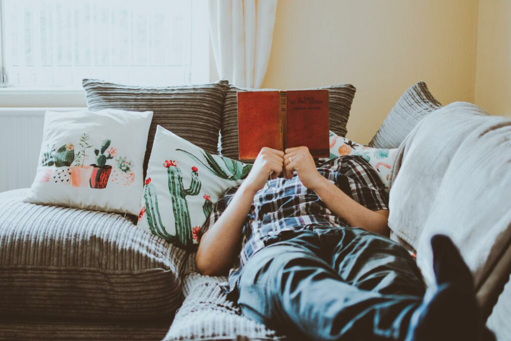 Is the 4-Day Work Week for You? Pros, Cons and Tips - Person Laying on Sofa While Reading Book