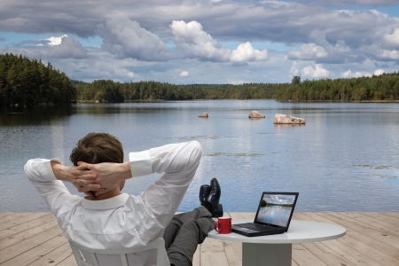 Enjoying a stress-free holiday - businessman relaxes by a lake