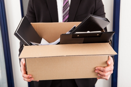 How to Survive a Job Loss - a young businessman holding a box of personal effects