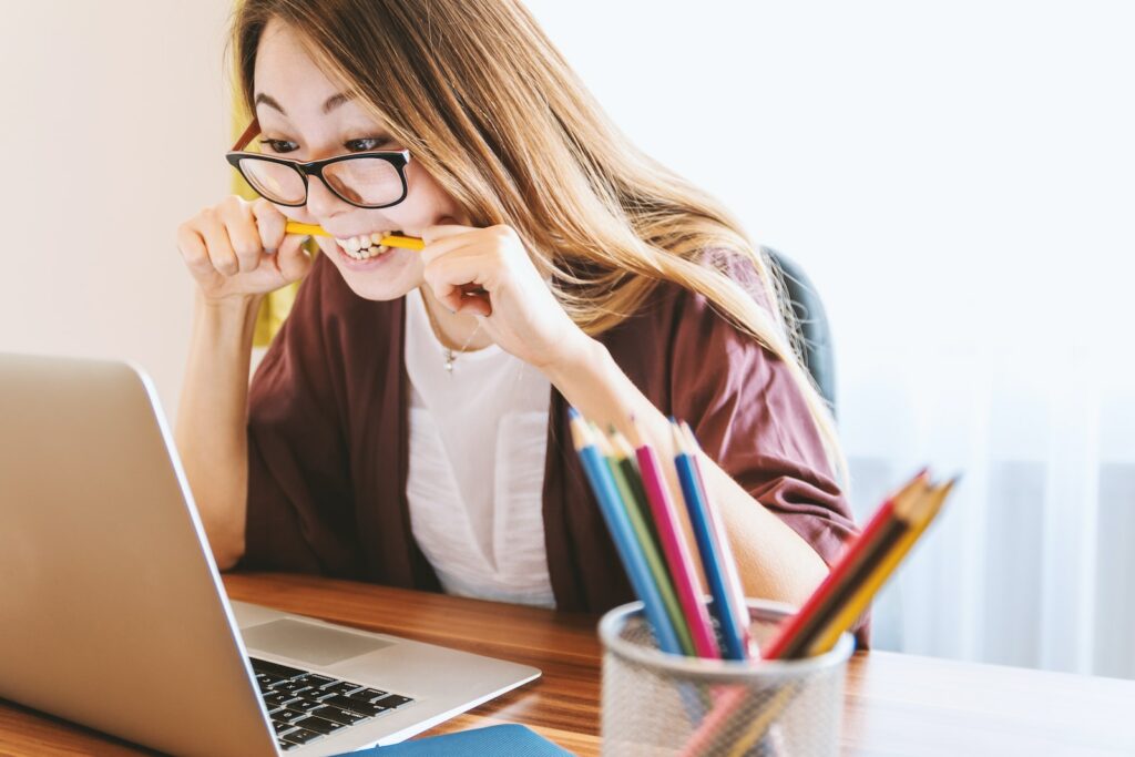 Debt management tips for small business owners - woman biting pencil while sitting on chair in front of computer