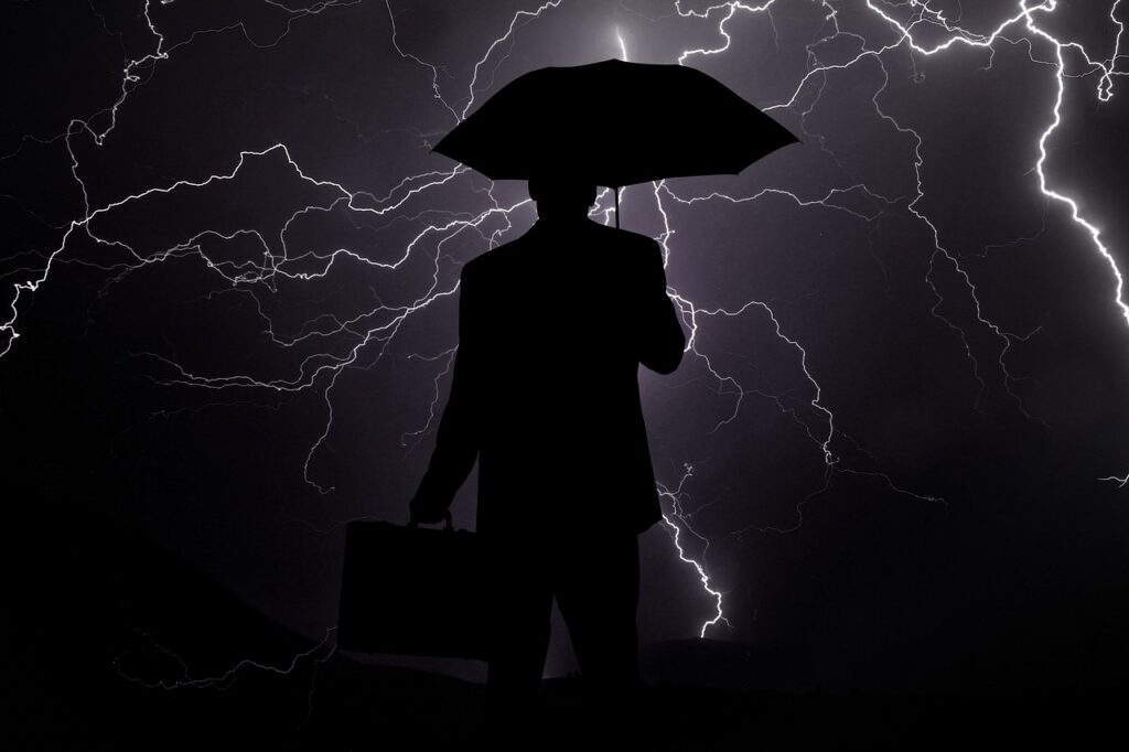 Business Update – 8 June 2023 - Be prepared for a recession, a businessman holding an umbrella in a lightning storm