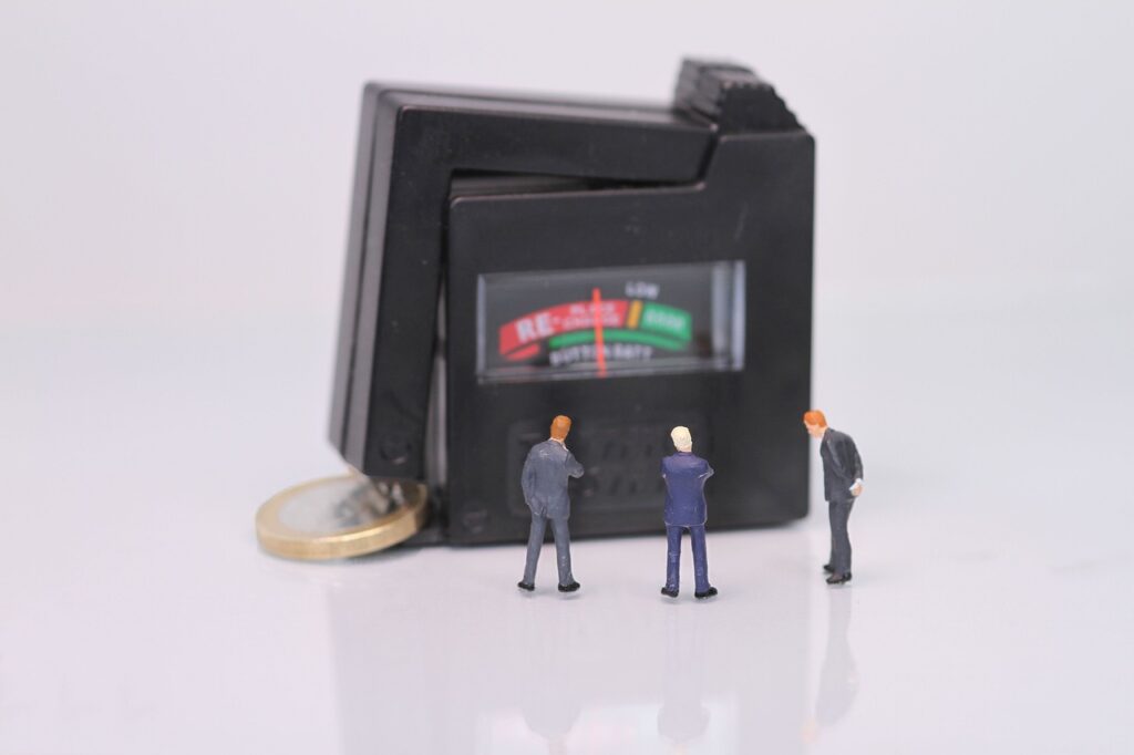 Business Update – 22 February 2024 - A battery tester testing a coin while observed by miniature figures