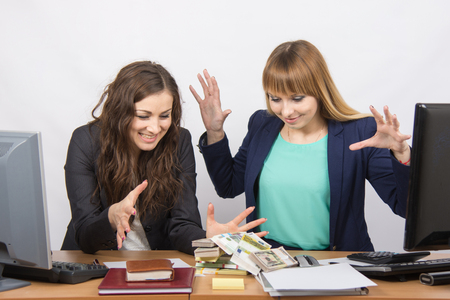 How to prevent employee theft -  two women collaborators about to grab a pile of money