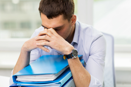 Common bookkeeping pitfalls - sad businessman with stack of folders at office