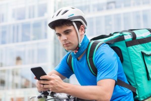 Could your business benefit from the gig economy? - courier on bicycle delivering food in city using mobile phone