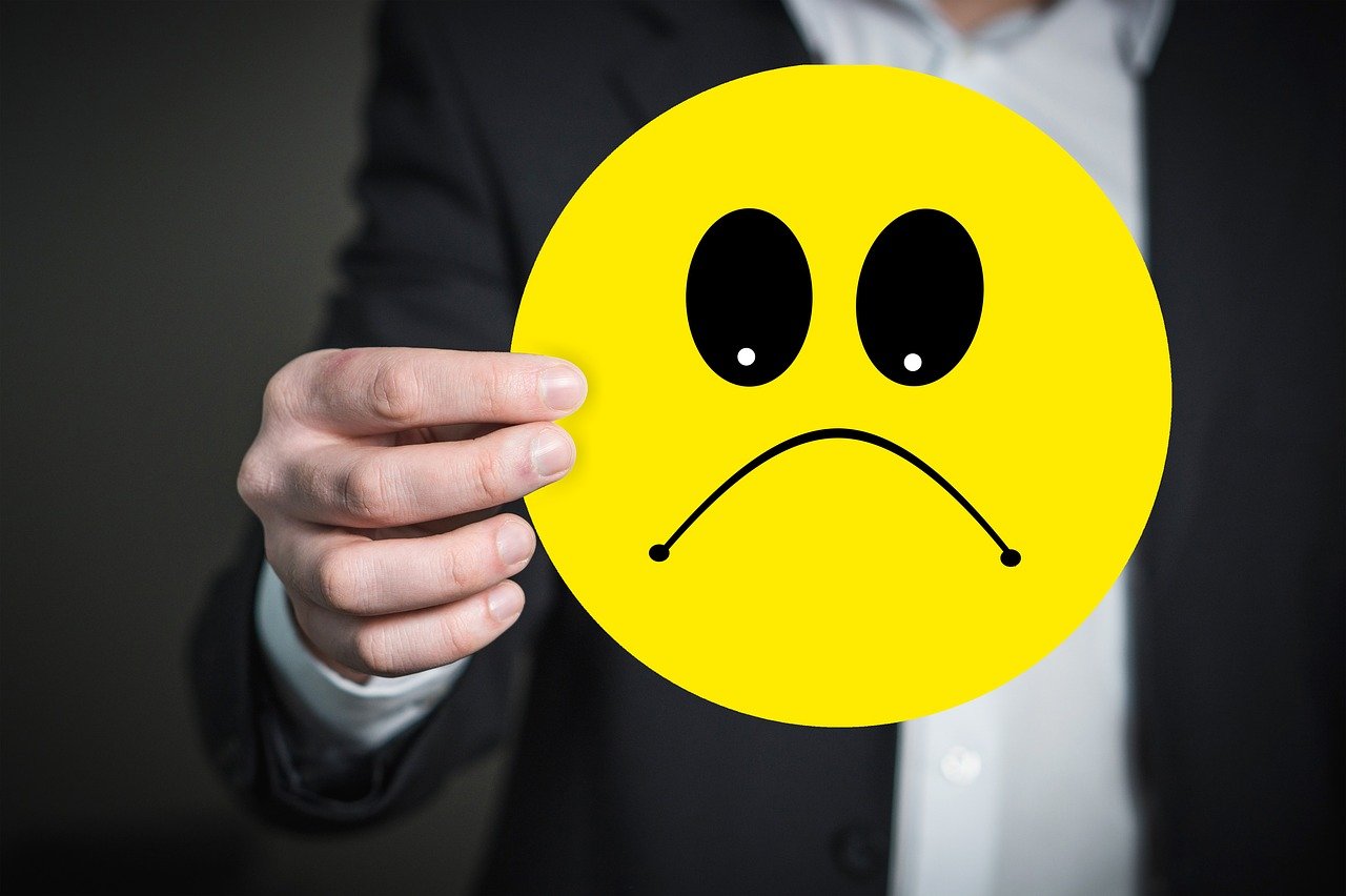 How to rebuild trust after a bad online review - a man holds an unhappy emoticon picture.