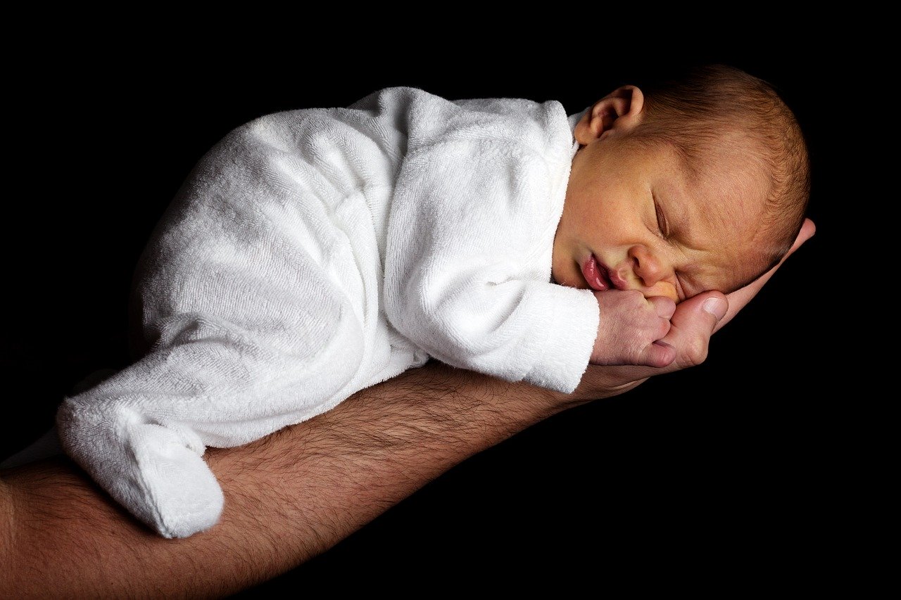 How to handle maternity and paternity leave - a baby held in the father's hand.