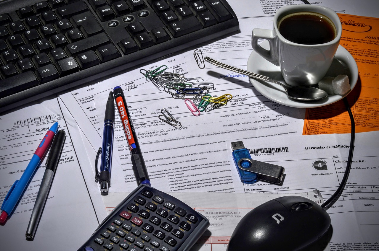 The common time waster that stops your business from growing - pens, calculator, paperclips and other stationery items litter a paper-strewn desk.