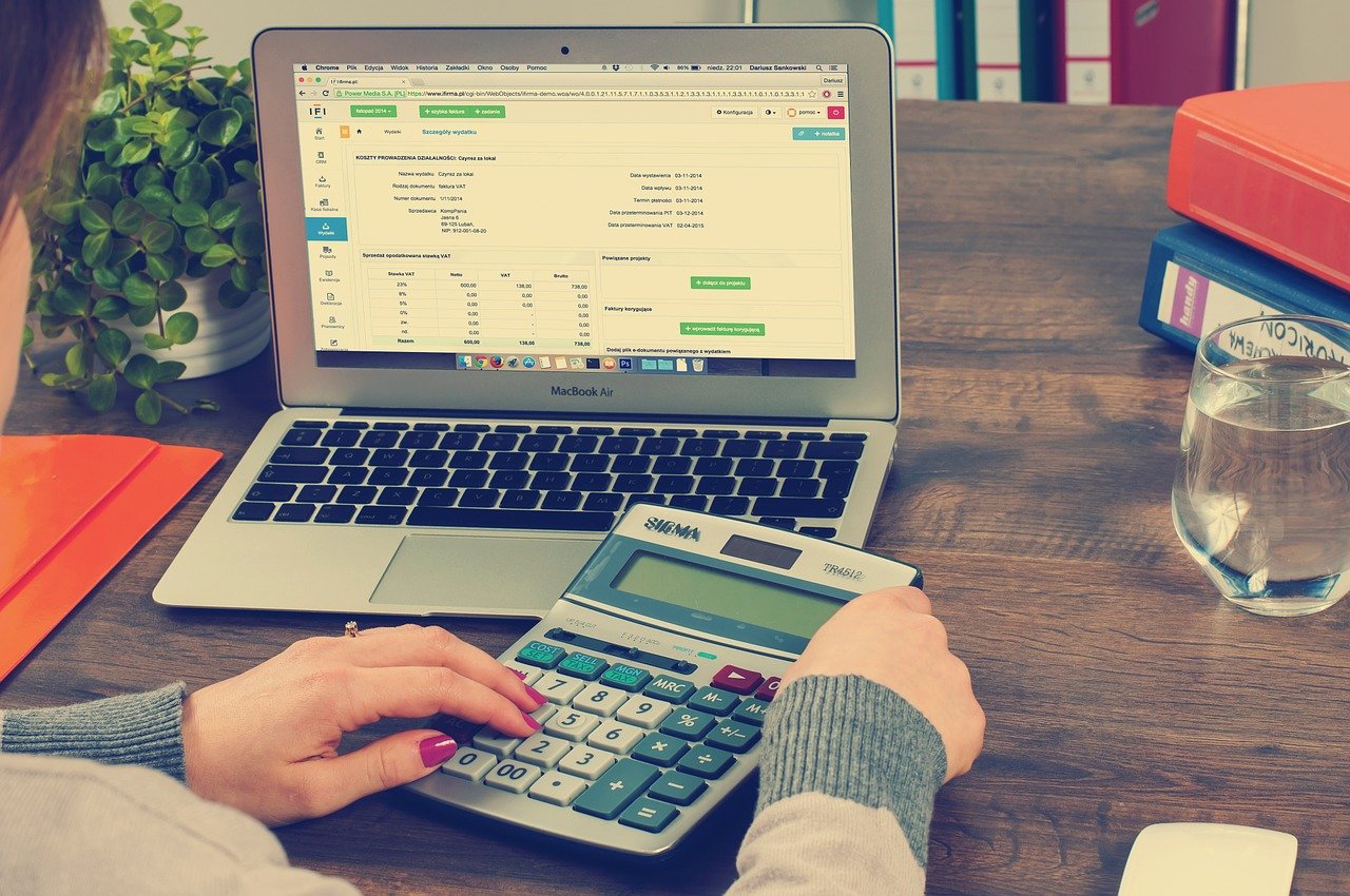 3 Consequences of Avoiding Your Bookkeeping - a woman uses a calculator and a notebook computer