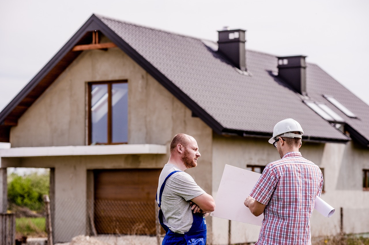 Three tips for managing construction industry cashflow - two builders having a discussion in front of a house.