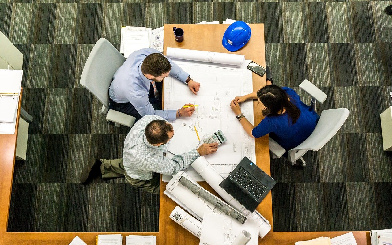 Want to chat about business plans for next year? Aerial view of three business people studying plans on a table