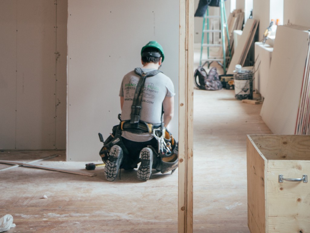Tips for managing contractors - construction worker kneeling in front of wall