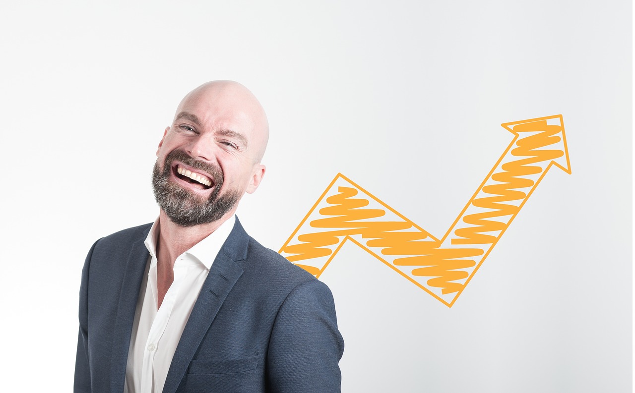 Business Update – 21 March 2022 - A laughing businessman in front of an upward-trending line graph.
