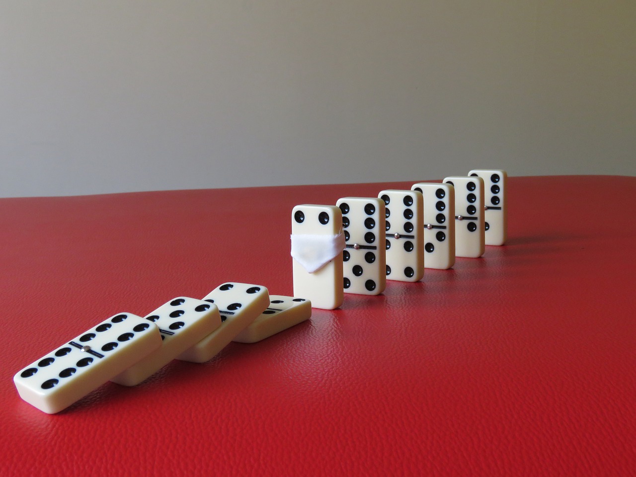COVID-19 Business Update - 7 September 2020 - a line of fallen dominoes is stopped by a domino wearing a face mask