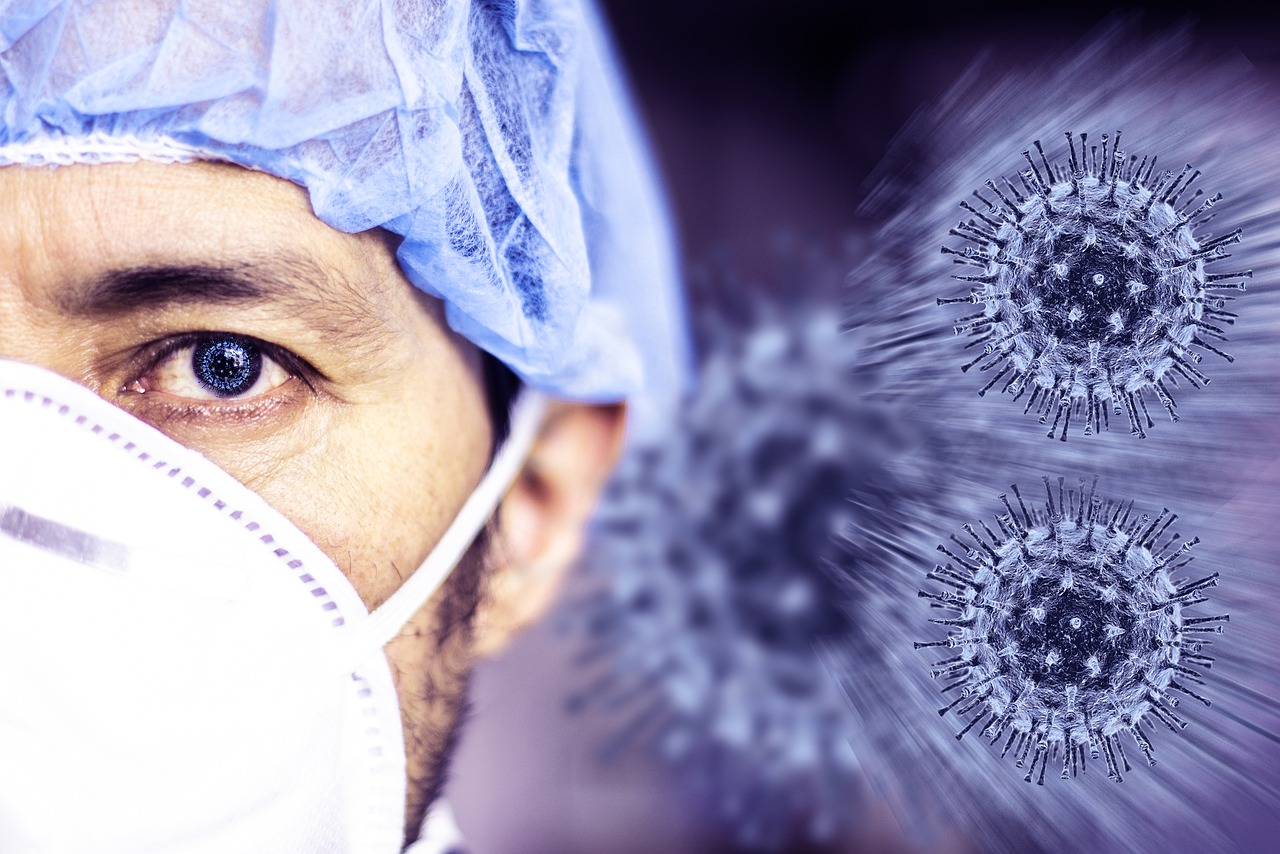 COVID-19 Business Update – 15 October 2020 - a doctor in mask and surgical cap before a background of magnified Coronaviruses.