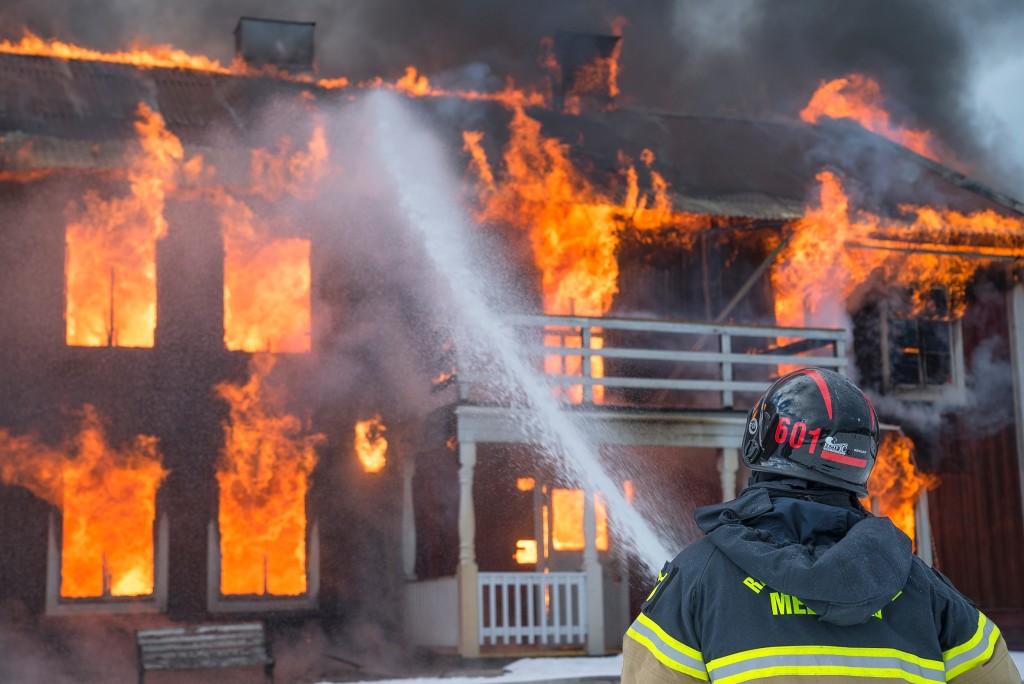 Is business insurance worthwhile? - Photo of fireman spraying water on burning building.