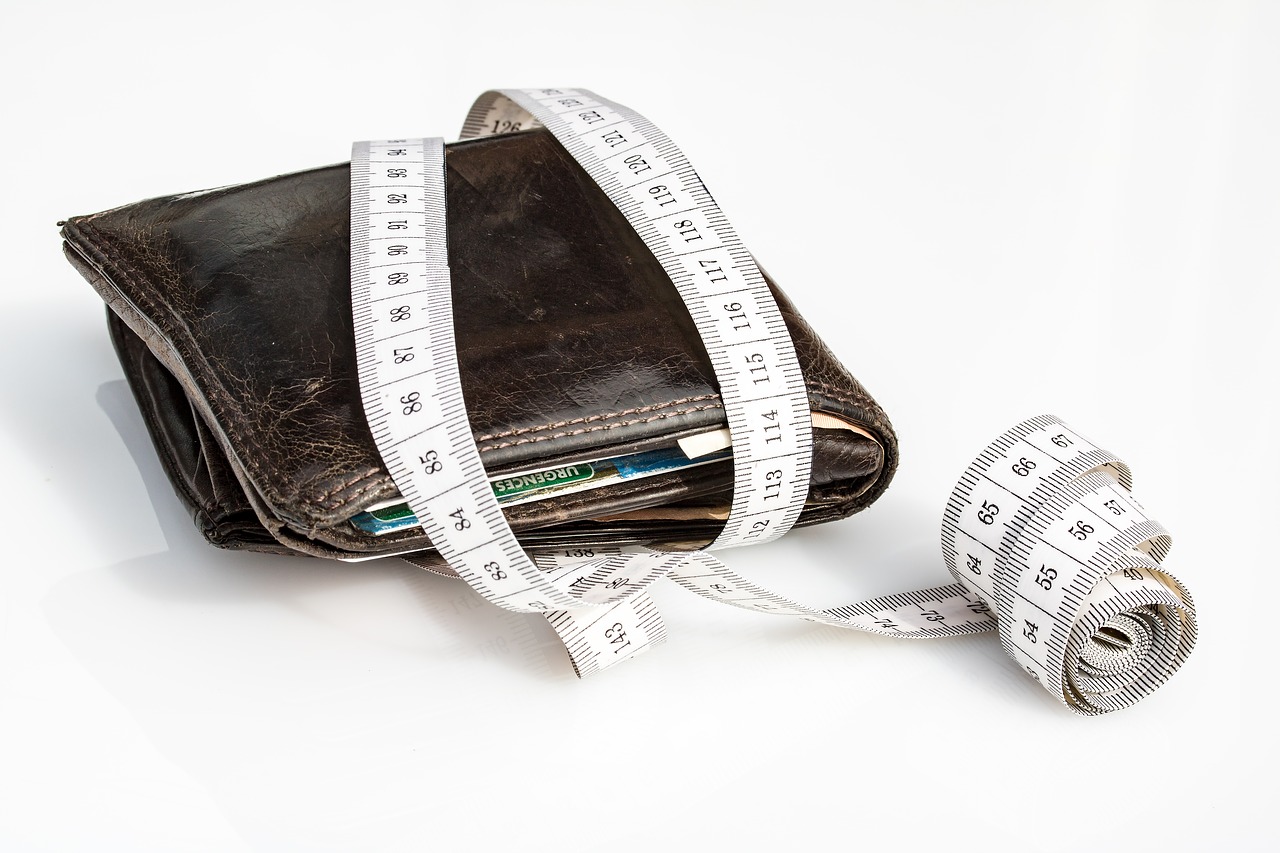 5 Tips to get out of debt faster - a wallet with a measuring tape wrapped around it.