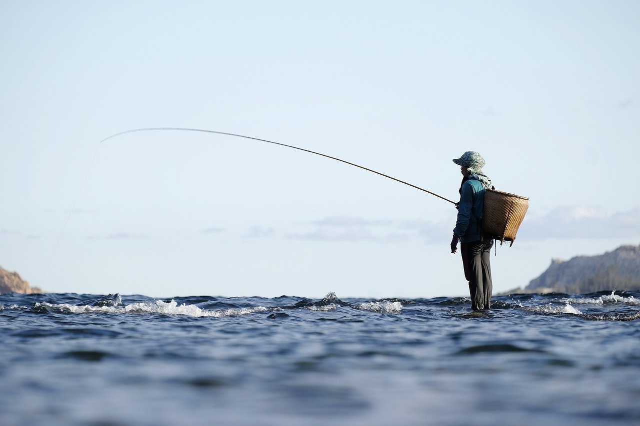 5 Steps to Early Retirement - A man stands fishing in the sea.