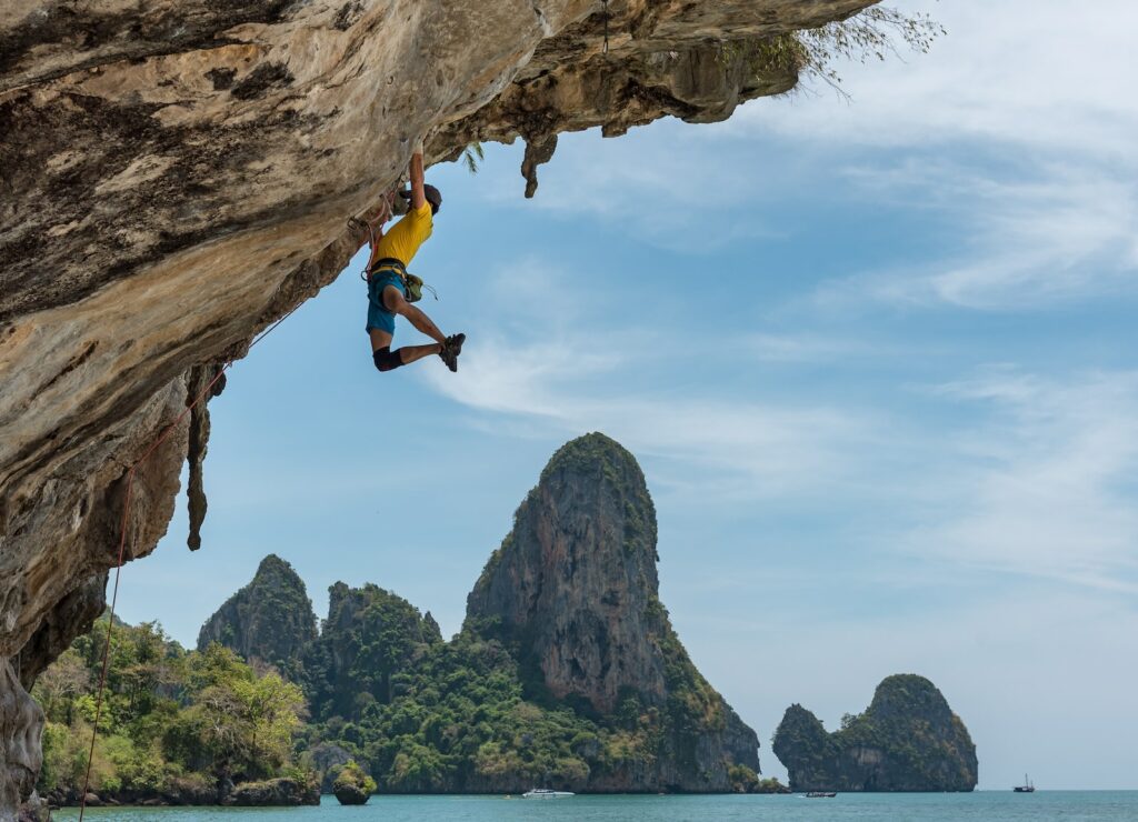 Differences between active and passive investing - A man climbing cliff beside beach