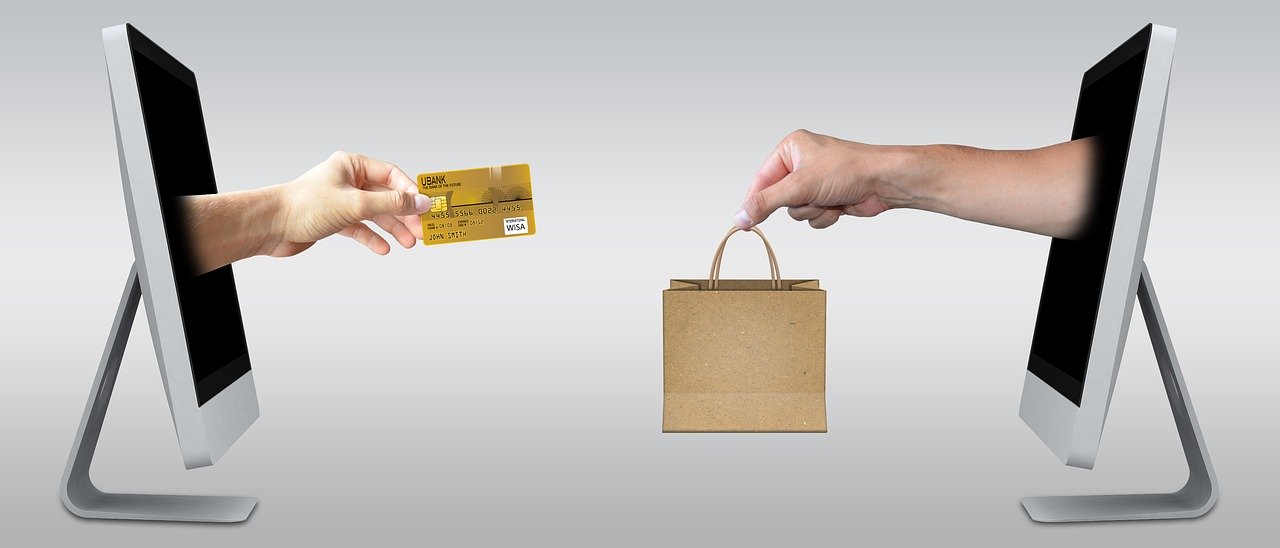 Easy ways to build an Online Business - A hand with a credit card reaches out from one computer screen towards a hand with a shopping bag reaching out from another computer screen.