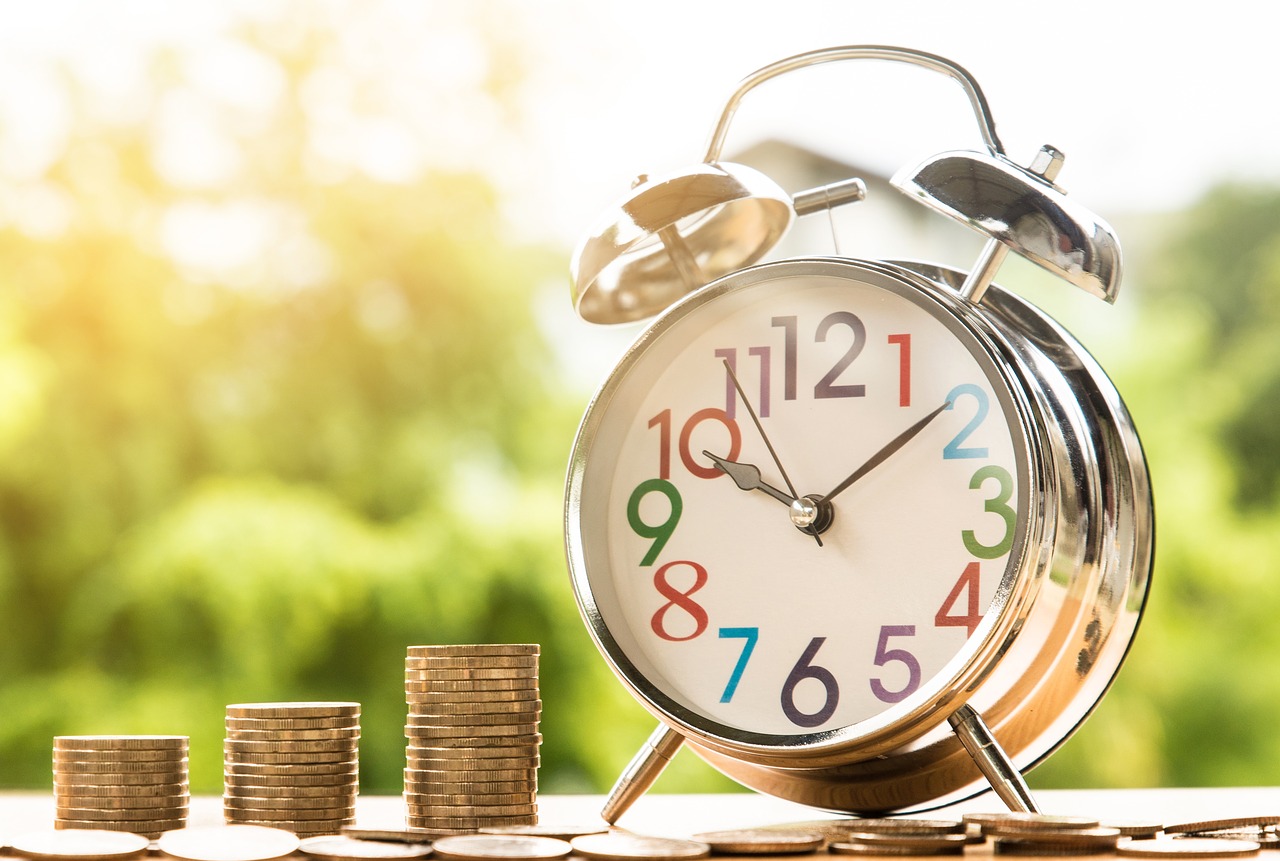 Superannuation guarantee amnesty - heaps of coins beside an old-style alarm clock. Take advantage of the amnesty while you have time.