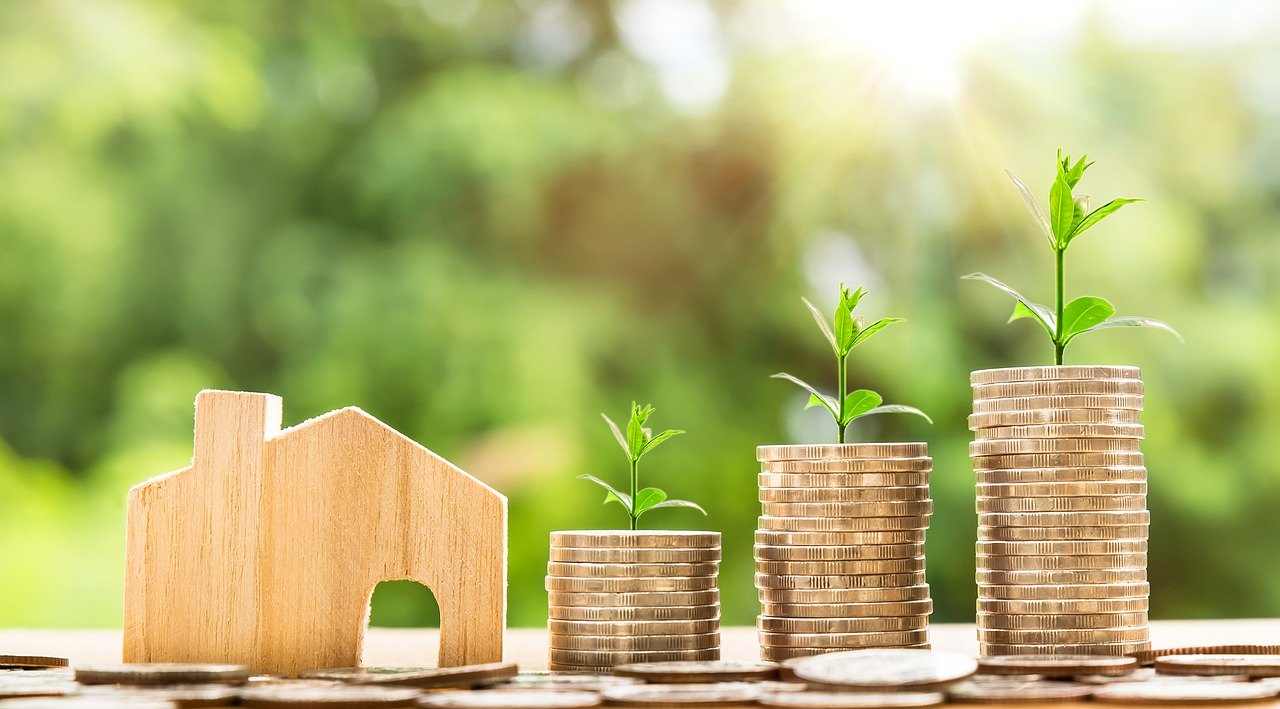 Can residential property fund your retirement? A wooden cutout house with towers of coins featuring growing plants forming an upward trending graph.