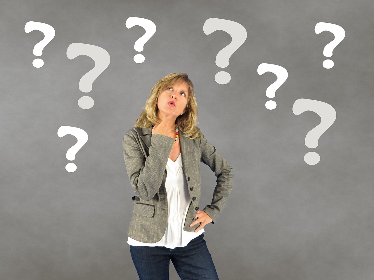 Small business questions to ask as you recover from COVID-19 - a woman ponders surrounded by question marks.
