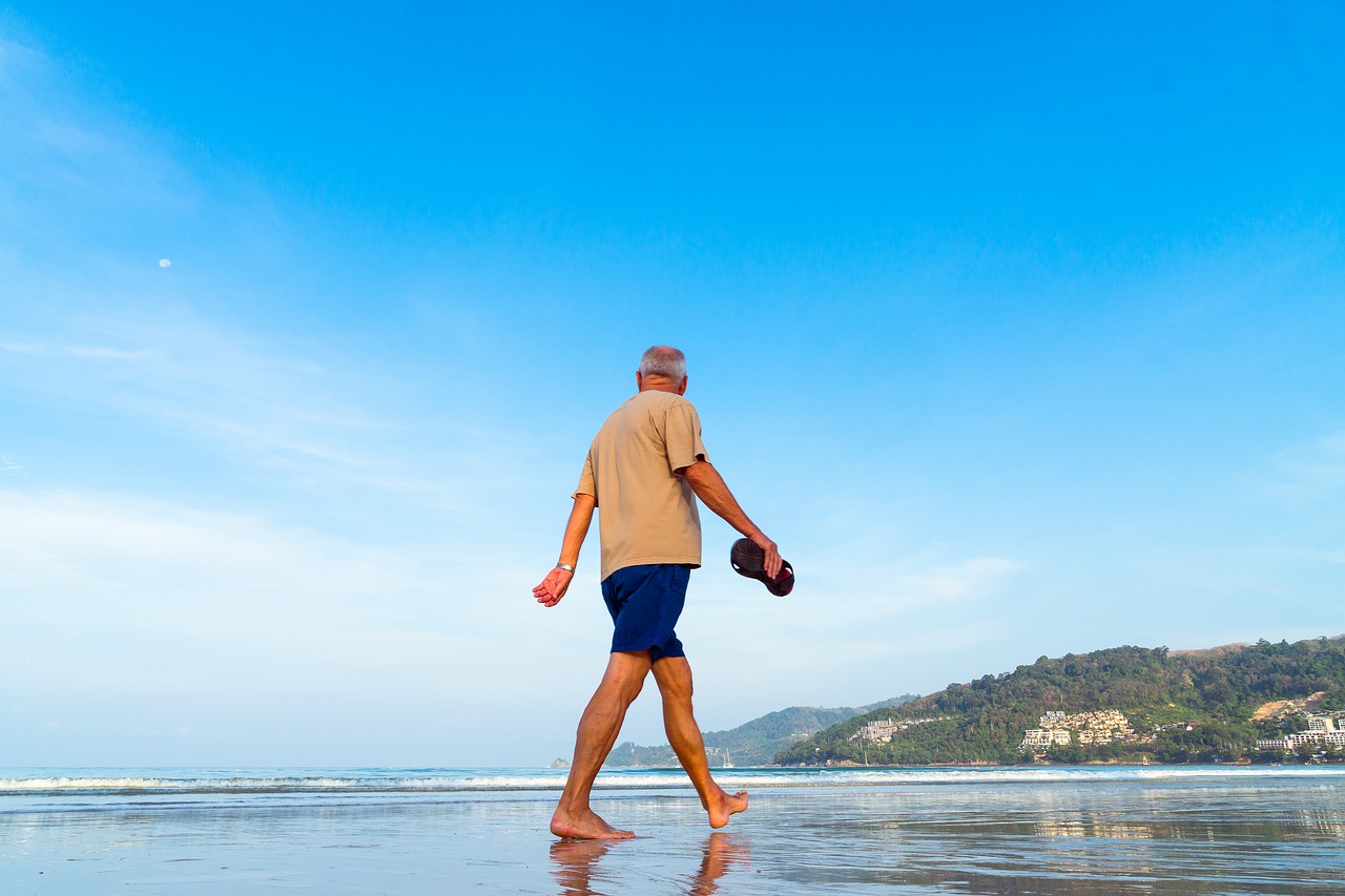 4 Steps to Retire Early - A fit grey-haired man walks along a beach looking at the sea