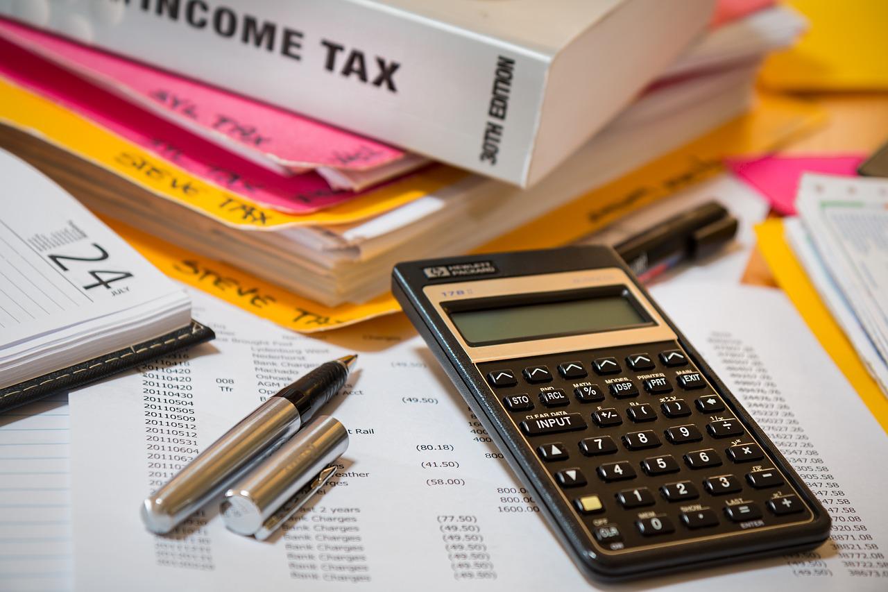 Year-end Tax Planning - pens, a calculator, and a book on income tax atop files and papers