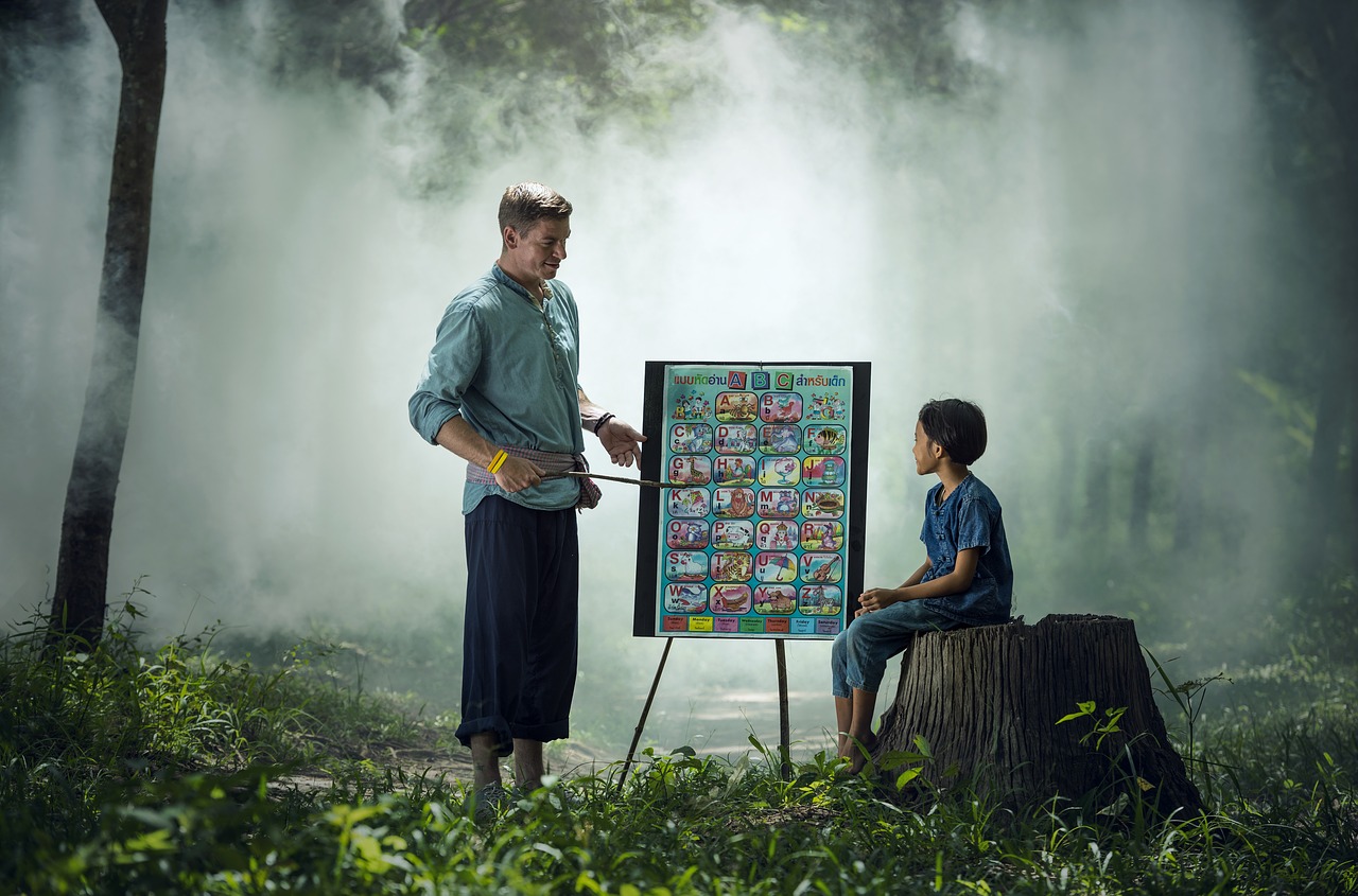 Life Lessons to Teach Your Kids If You Want Them To Succeed - a man teaches his son seated on a tree stump in a misty forest with the aid of a flip chart