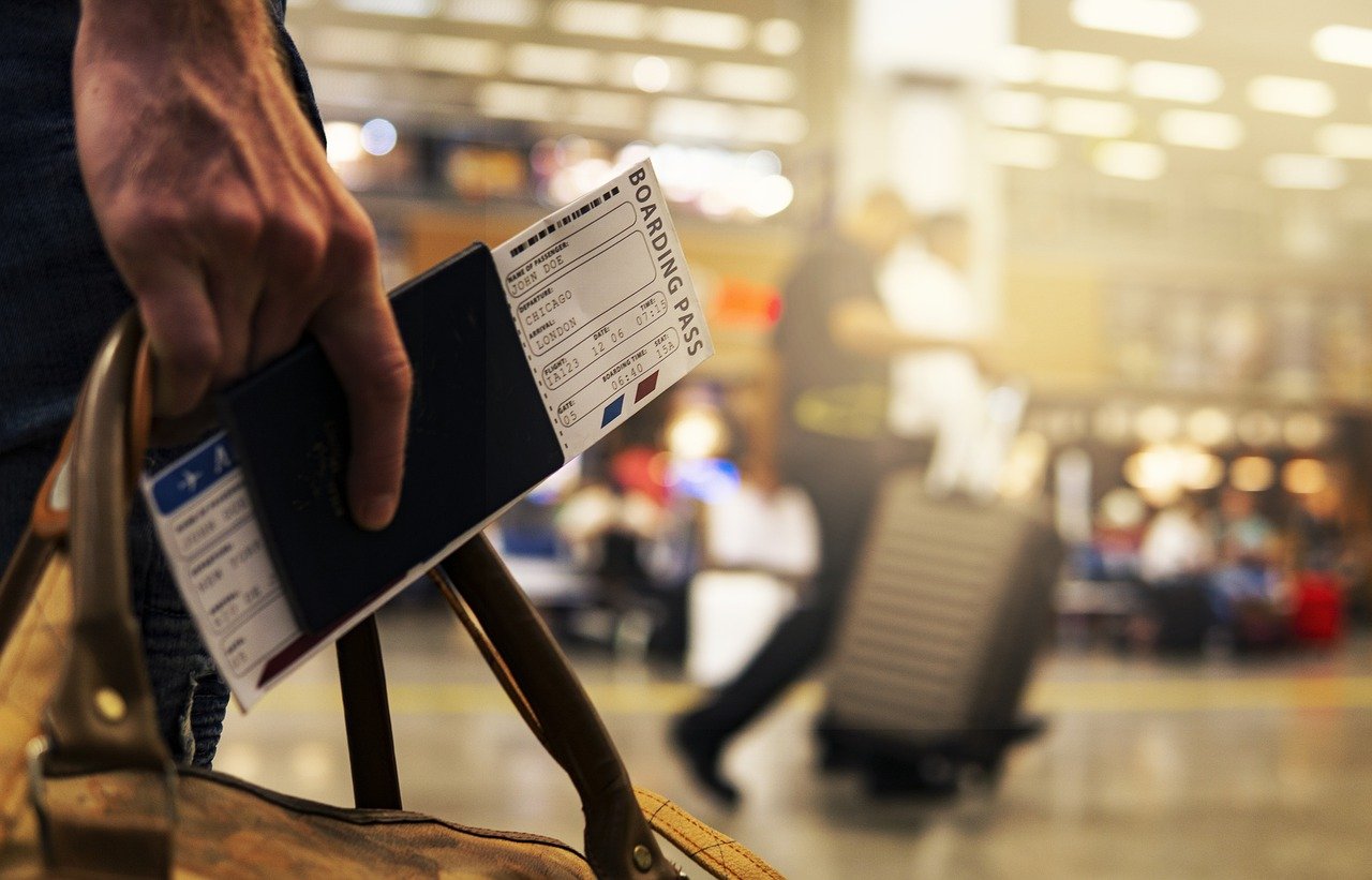 Business Update – 22 April 2022 - a passenger in an airport terminal holding a passport and boarding pass.