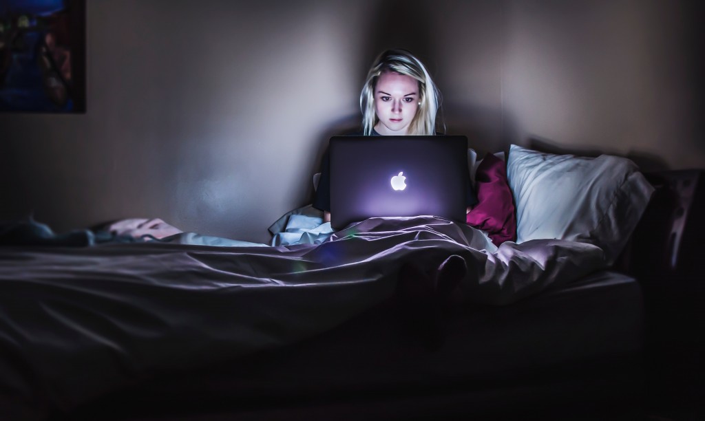 Protect yourself and your data - photograph of woman sitting on bed in the dark with her notebook computer